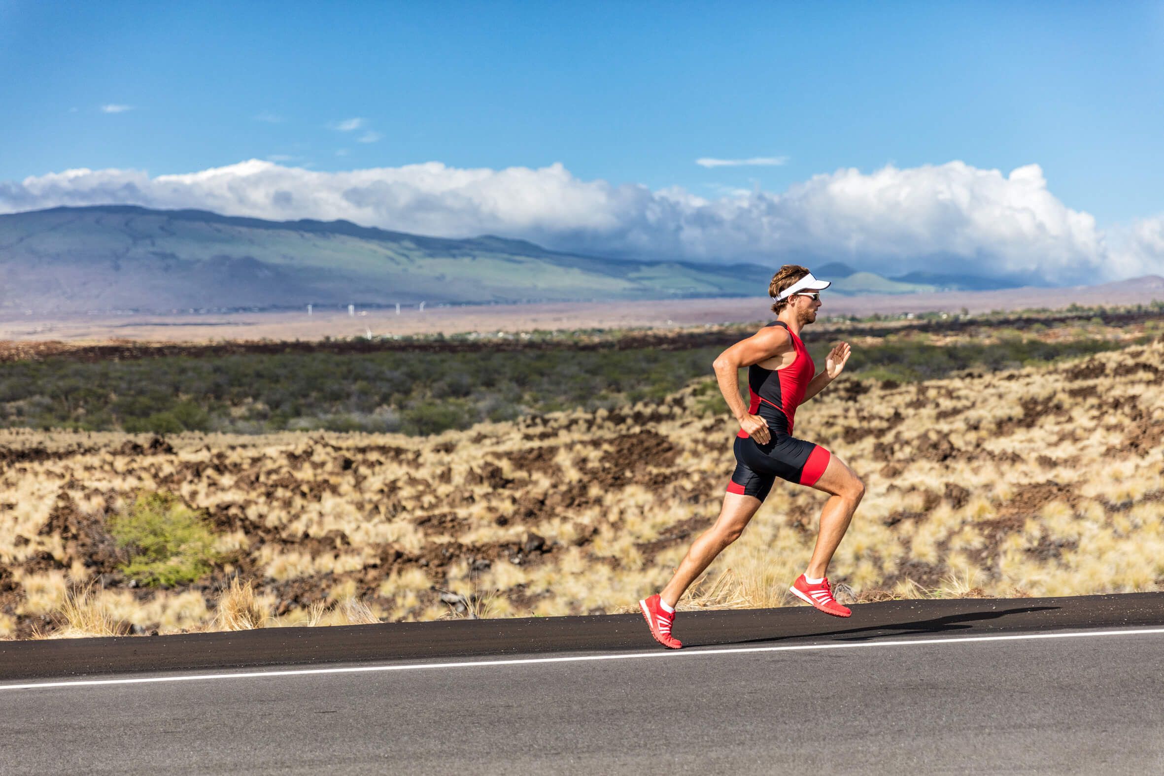 a triathlete runs along a road against a wild landscape