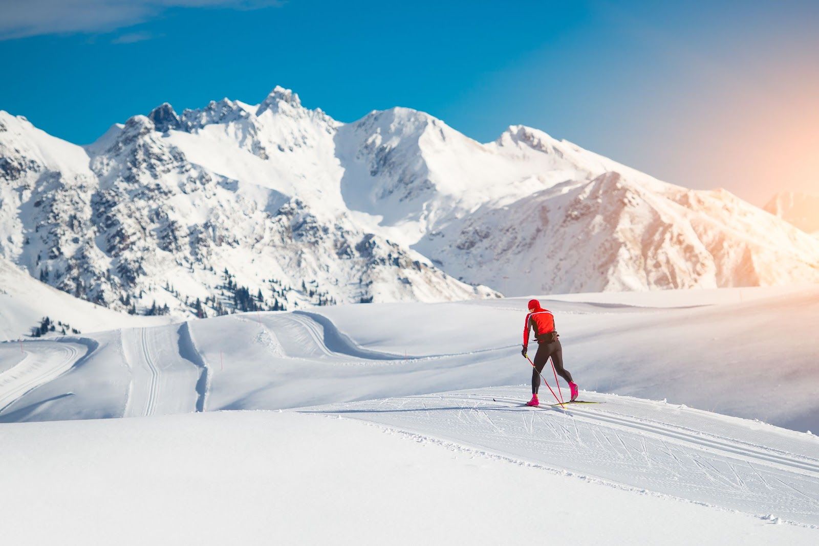 a cross-country skier skiing on the well-prepared slopes in sunny weather