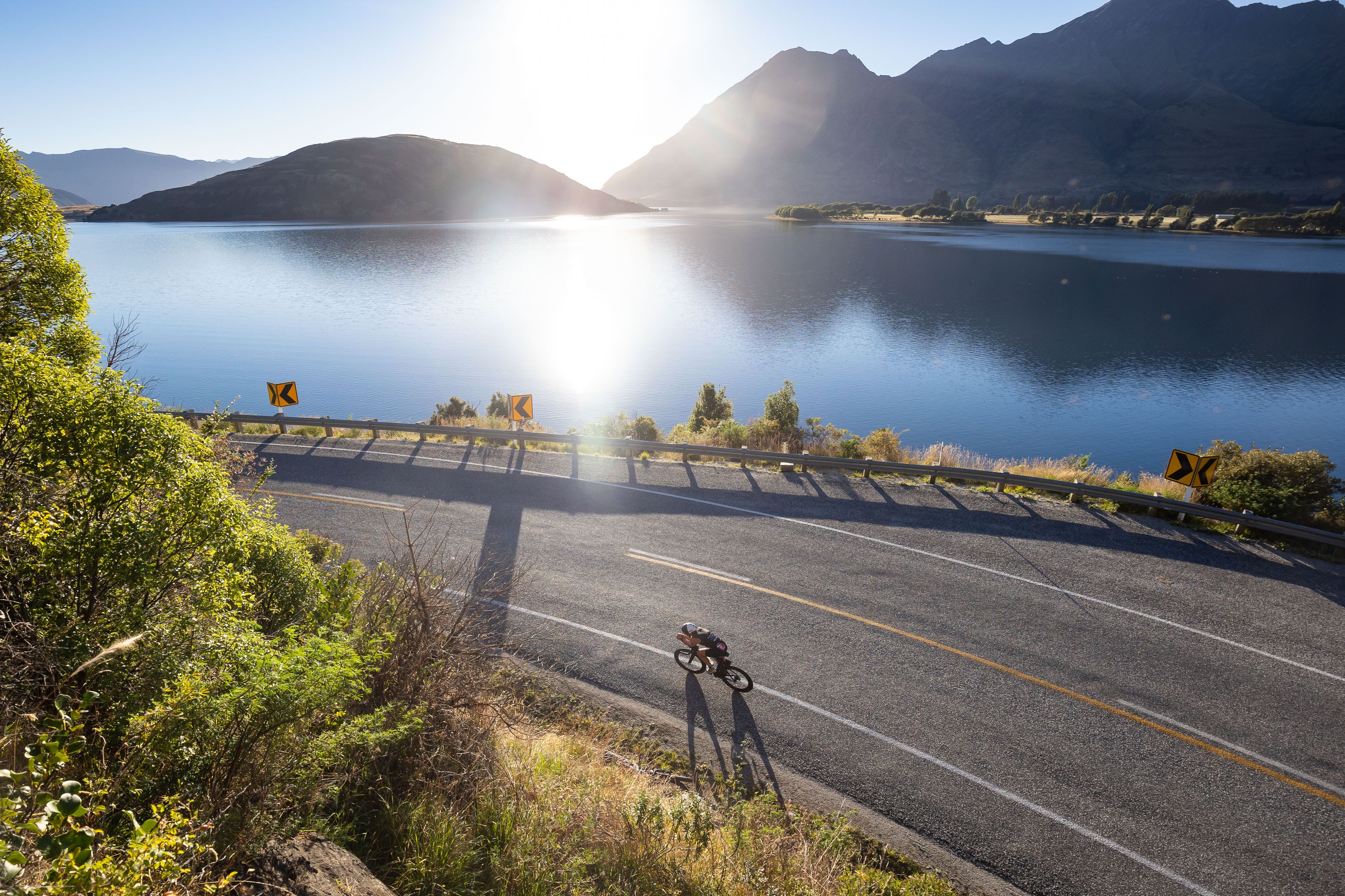 Triathlon cyclist riding on road beside lake